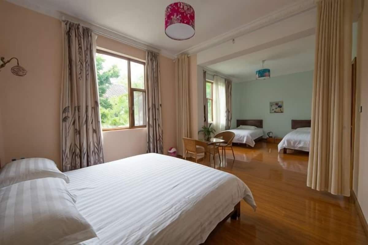 A bedroom with a large bed, a desk, and two smaller beds.
