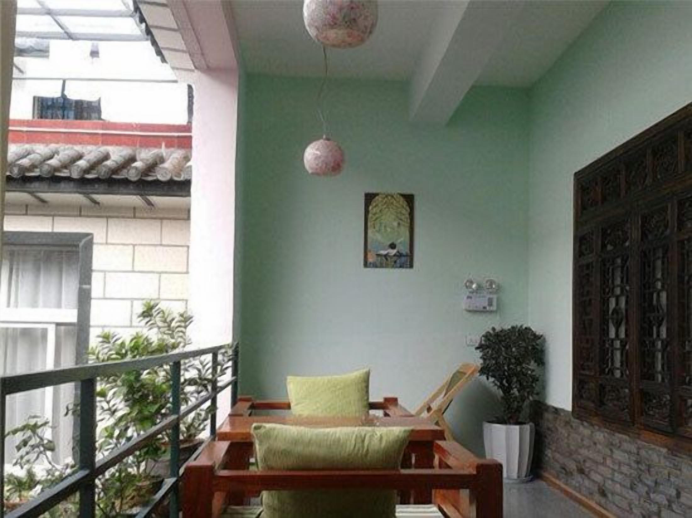 Un balcon avec une chaise en bois, un coussin, une suspension et une plante en pot.