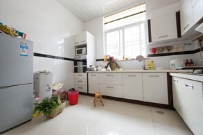 A kitchen with white cabinets, a refrigerator, a microwave, and a window. - Dali Ancient City Xiaoqiang Craft Theme Homestay (Dali City)