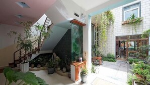 Amplio espacio interior con una escalera, plantas en macetas y vistas al exterior.