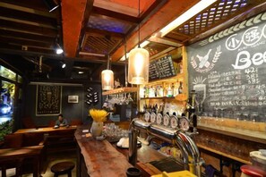 Un bar con un menú en pizarra, luces colgantes y una variedad de botellas.