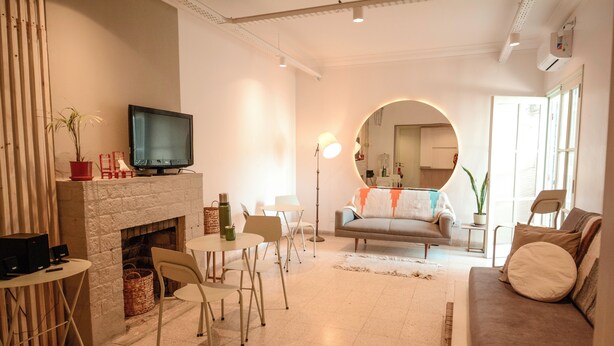 A living room with a fireplace, a television, a round mirror, and a sofa. - Exclusiva Casa en una de las Mejores Zonas de Mendoza (Buenos Aires)