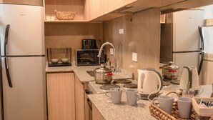A compact kitchen with a refrigerator, stove, toaster, and kettle. - Exclusiva Casa en una de las Mejores Zonas de Mendoza (Buenos Aires)