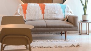 A modern living room with a round mirror, a sofa, a coffee table, and a potted plant. - Exclusiva Casa en una de las Mejores Zonas de Mendoza (Buenos Aires)