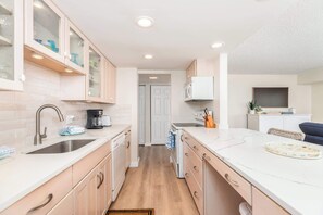 A modern kitchen with a sink, stove, and cabinets. - Ocean Front Condo with Sunrise Views (Ocean City)