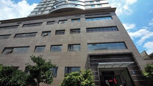 A multi-story building with a curved facade, large windows, and a visible entrance area with people and greenery. - Yunjie Apartment Hotel (Kunming)