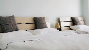 A bed with white bedding and two pillows, a wooden headboard, and a bedside lamp. - Yunjie Apartment Hotel (Kunming)