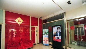 A lobby with a red sofa, a glass door, and a poster on the wall. - Yunjie Apartment Hotel (Kunming)