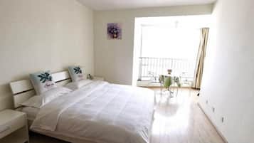 Une chambre à coucher comprenant un lit, des tables de chevet, une petite table avec des chaises et un balcon doté d’une balustrade.