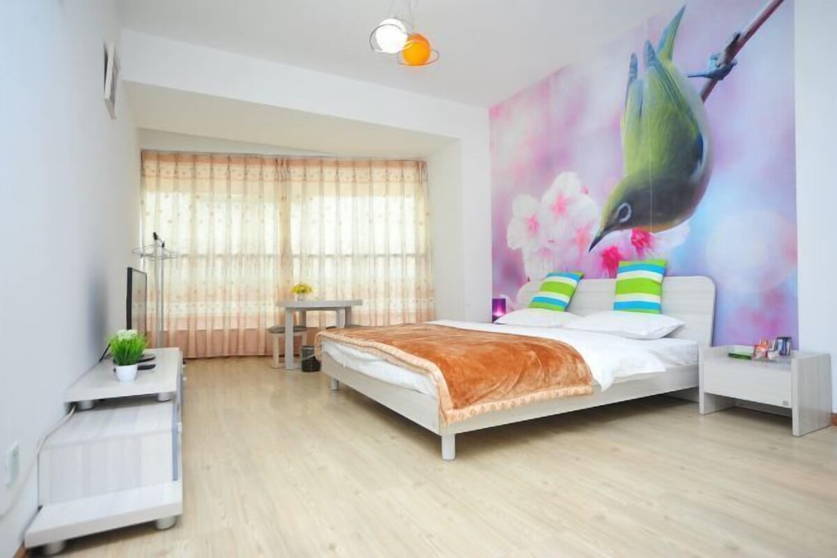 A bedroom with a bed, a nightstand, a desk, and a chair.