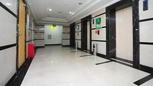 A hallway with white tiled floors, black and white walls, and doors with black marble frames. - Yunjie Apartment Hotel (Kunming)