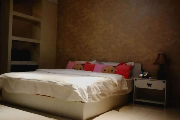 Un dormitorio con una cama, una mesita de noche y una unidad de pared.