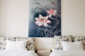 Une chambre d’hôtel avec un lit, une table de chevet et une grande œuvre d’art florale accrochée au mur.