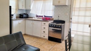 A compact kitchen with white cabinets, a gas stove, a microwave, and a sink. - Cozy 1-bedroom apartment in peaceful Valley with AC, WiFi (Cassada Gardens)