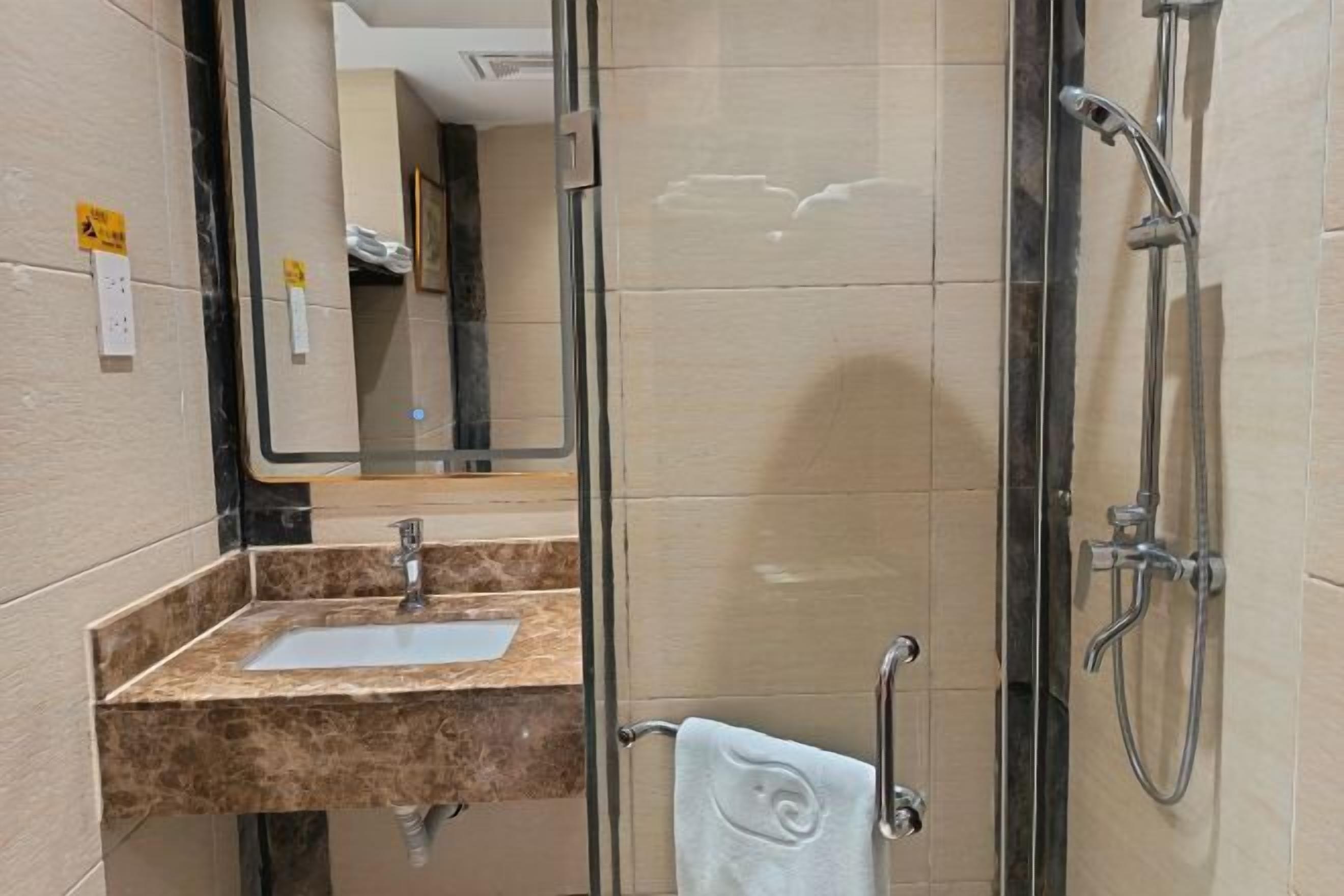 A bathroom with a marble sink, a glass shower enclosure, and a towel rack.