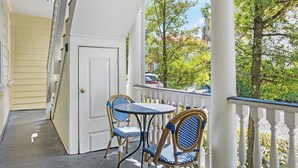 A porch with a white railing, a door, and two wicker chairs with blue cushions.