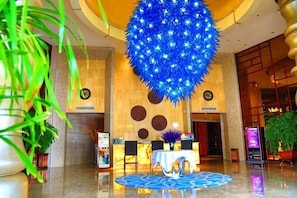 Een hal met een grote blauwe bolvormige decoratie, een receptiebalie en een klok aan de muur.