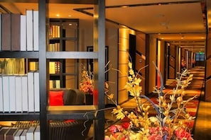 Un pasillo de hotel con una estantería, un sofá y un arreglo decorativo de plantas.