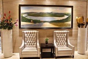 Una habitación con dos sillones, una mesita y un cuadro de un paisaje en la pared.