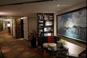 Un vestíbulo de hotel con una estantería, una zona de estar y un cuadro grande de un paisaje urbano.