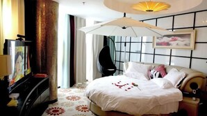 A hotel room with a large bed, a TV, a desk, and a unique ceiling light fixture. - Beau Upward Maylily Hotel (Yinchuan)