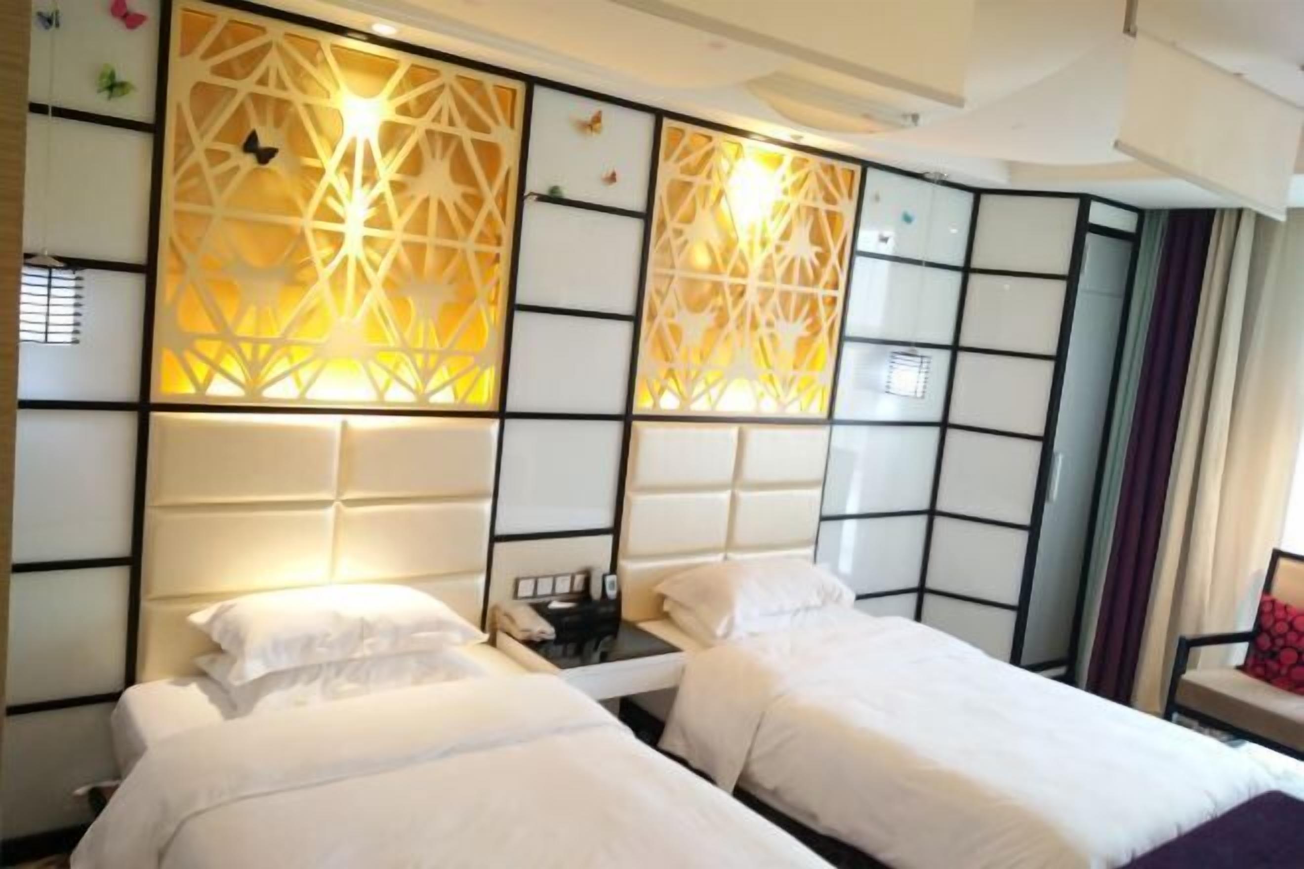 Habitación de hotel con dos camas, un enrecado de pared con motivos geométricos y una mesita de noche con un teléfono.