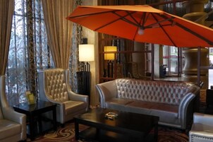 Un hall de hotel con un sofá, sillones, una mesa de centro y un paraguas.