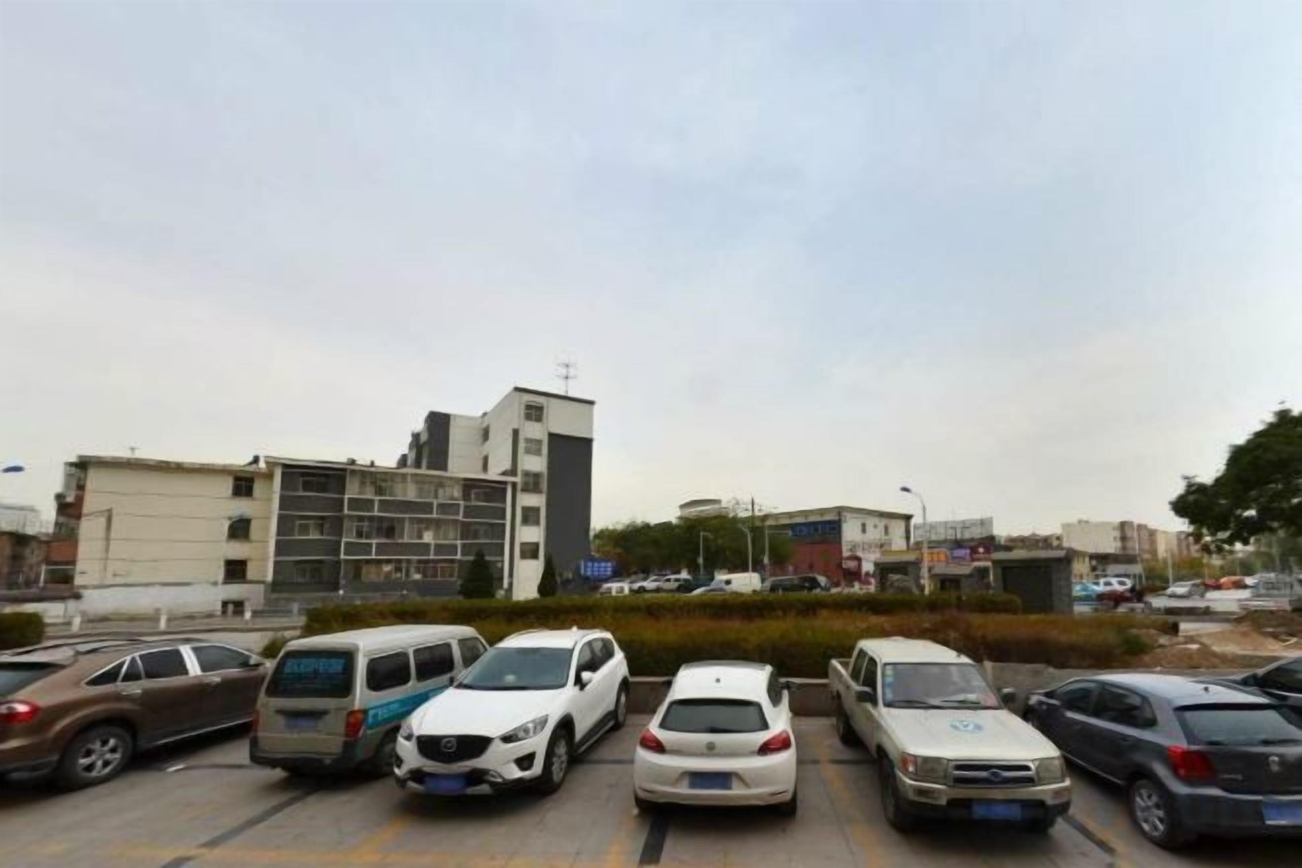 A parking lot with several cars and a building in the background.