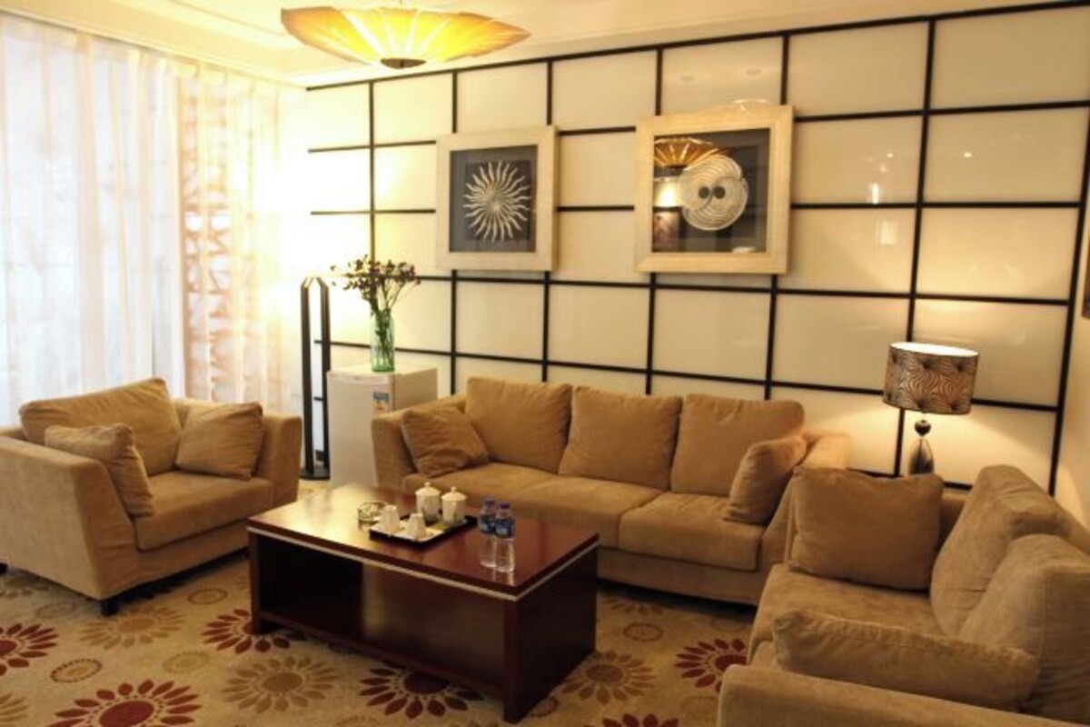 Habitación de hotel con sofá, una mesa de centro, lámpara y cuadros en la pared.
