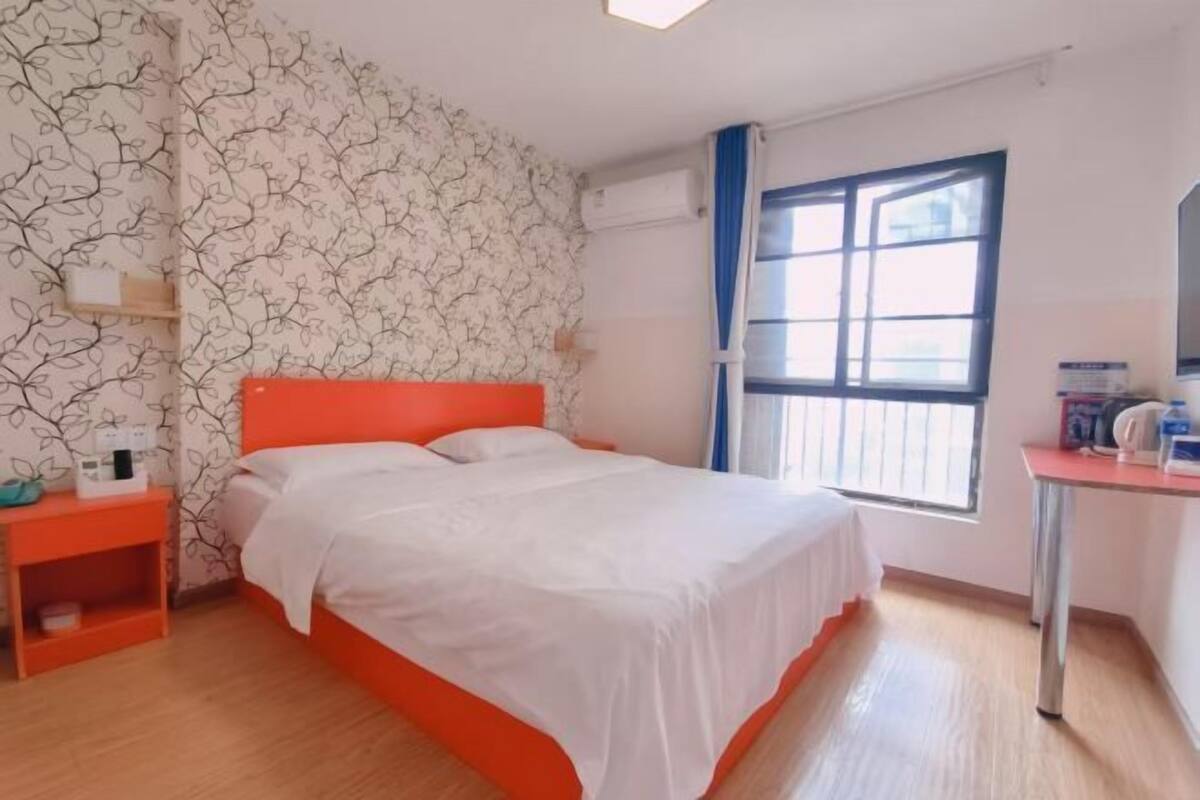 Ein Zimmer mit einem Bett, einem Nachttisch, einem Fenster und einem Schreibtisch.