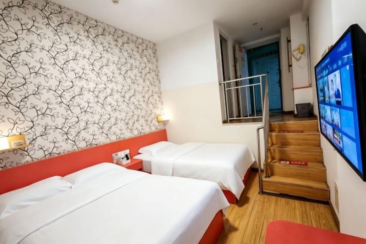 Une chambre d’hôtel avec deux lits, une télévision et un escalier.