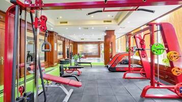 Een sportschool met diverse fitnessapparaten, waaronder krachtapparaten en banken.