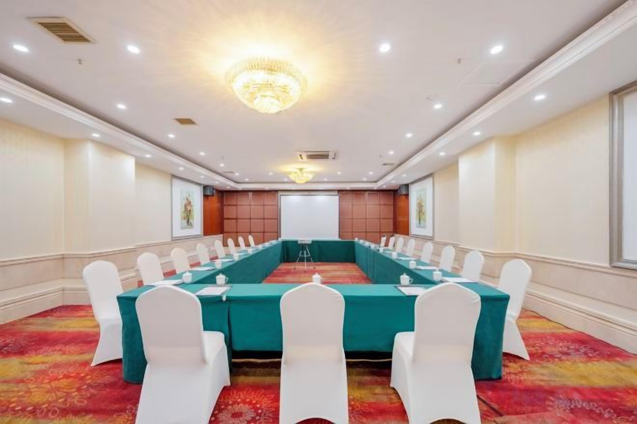 A conference room with a long table, white chairs, and a carpeted floor.