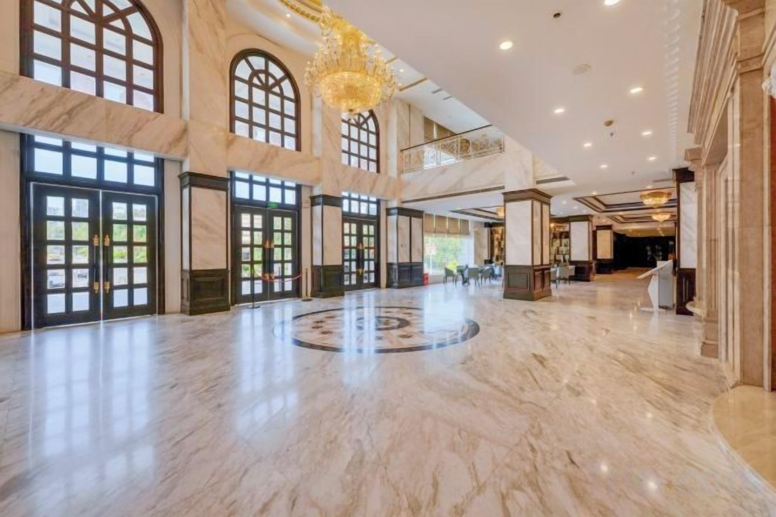 A spacious lobby with marble flooring, large windows, and a grand chandelier.