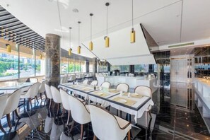 A modern restaurant with a long communal table, high ceilings, and large windows. - Light Grand Hotel (Fengdu County)