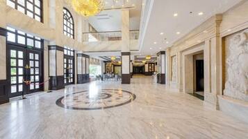 A spacious lobby with marble flooring, large windows, and a grand chandelier.
