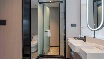 A modern bathroom with a glass shower enclosure, a white sink, and a large mirror.