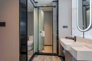 A modern bathroom with a glass shower enclosure, a white sink, and a large mirror. - Light Grand Hotel (Fengdu County)