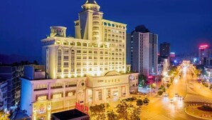 A multi-story hotel with a central tower, a large entrance, and a well-lit street in the foreground. - Light Grand Hotel (Fengdu County)