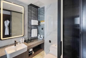 Une salle de bain moderne avec un grand miroir, un lavabo, un porte-serviettes et des toilettes.
