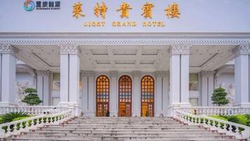 Het uiterlijk van het Light Grand Hotel, met een statig entree, trappen die naar de deuren leiden en een symmetrische gevel met kolommen.