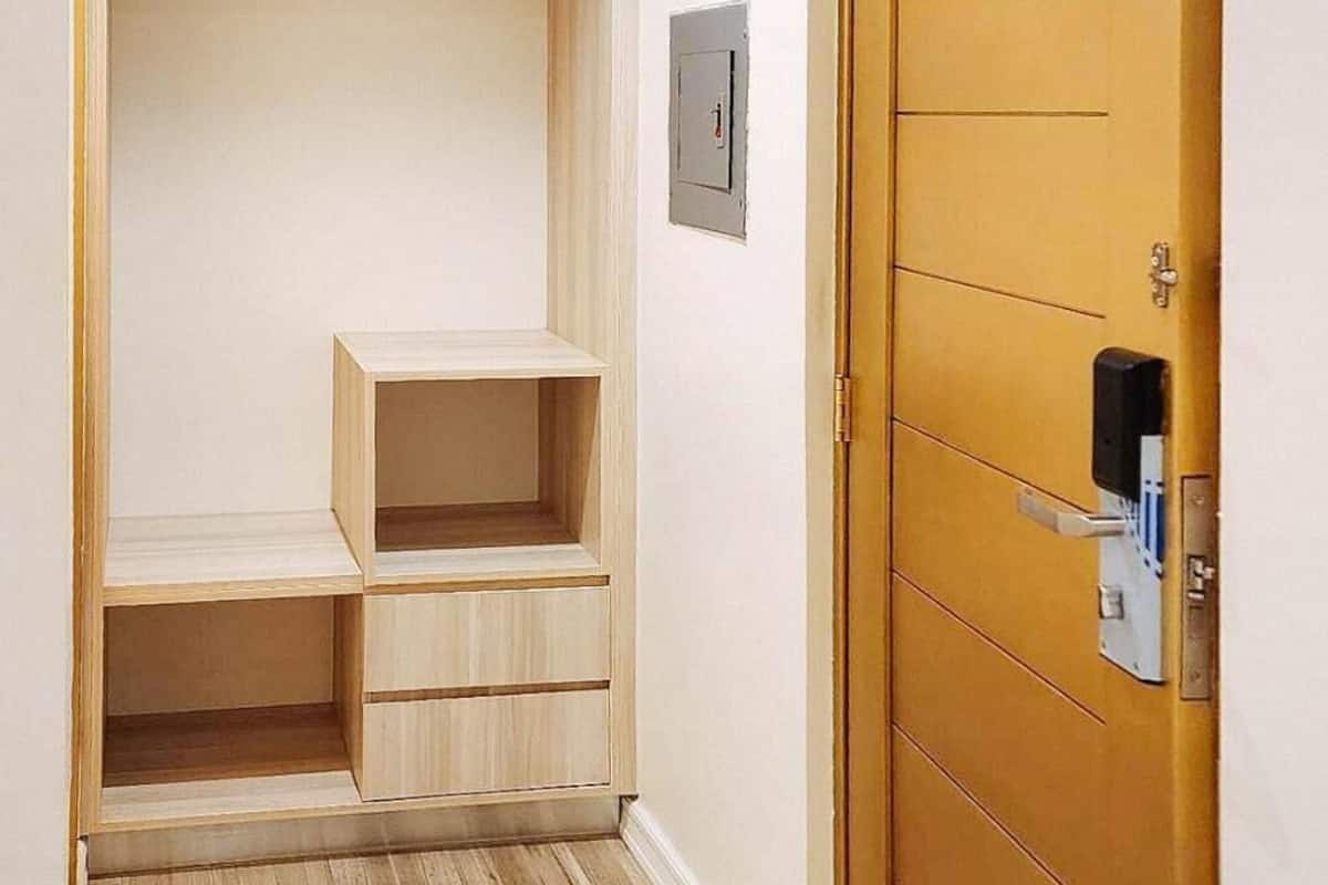 Una habitación con un armario de madera, una estantería pequeña y una puerta con cerradura.