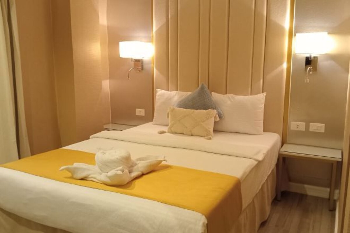 A hotel room with a bed, a bedside table, and a nightstand.