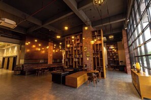 A spacious indoor area with a bar, seating, and bookshelves. - Zhehui Hotel (Zhongshan)