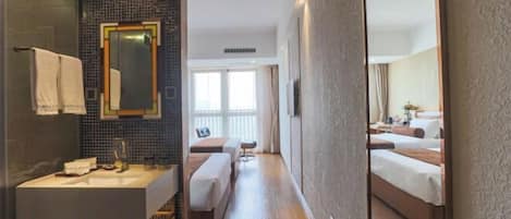 A hotel room with a large mirror, a sink, a bedside table, a bench, and a bed with a headboard.