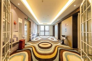 A hotel corridor with patterned carpet, glass doors, and a view of the city. - Zhehui Hotel (Zhongshan)