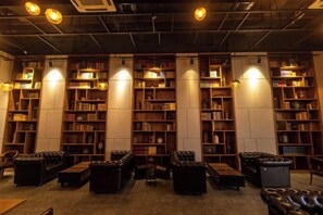 A library with bookshelves, leather seating, and ceiling lights. - Zhehui Hotel (Zhongshan)