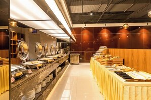 Montaje tipo bufé con varias estaciones de servicio, una larga barra y una gran variedad de alimentos.
