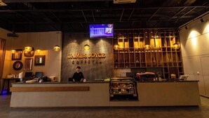 A reception area with a counter, a digital screen, and a coffee bar. - Zhehui Hotel (Zhongshan)