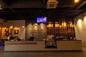 A reception area with a counter, a digital screen, and a coffee bar. - Zhehui Hotel (Zhongshan)